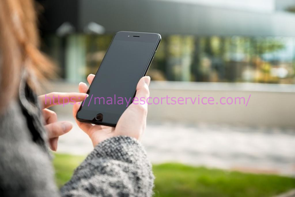 Woman using smartphone, searching for KL call girl services online.