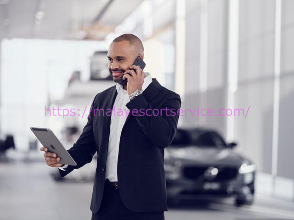 Businessman using phone and tablet in car showroom