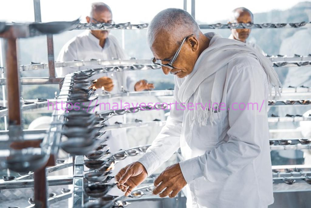 Man lighting oil lamps in a temple, practicing a religious ritual.