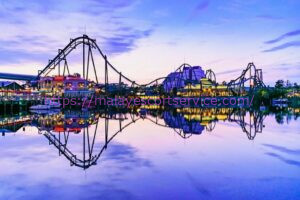 Night view of Universal Studios Japan (USJ) amusement park with roller coasters reflecting in a calm lake.