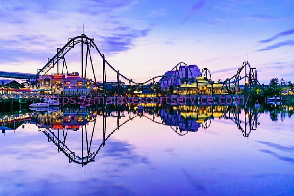 Night view of Universal Studios Japan (USJ) amusement park with roller coasters reflecting in a calm lake.