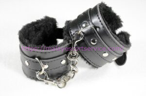 Black leather and fur handcuffs with a metal chain.