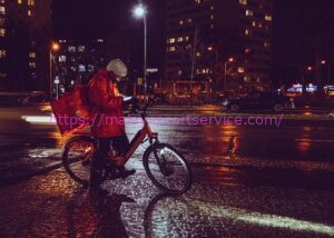 Delivery person on bicycle at night in the rain