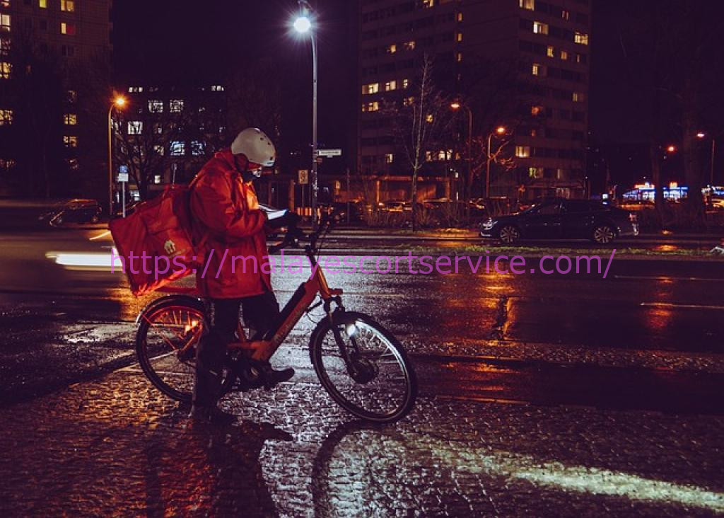 Delivery person on bicycle at night in the rain
